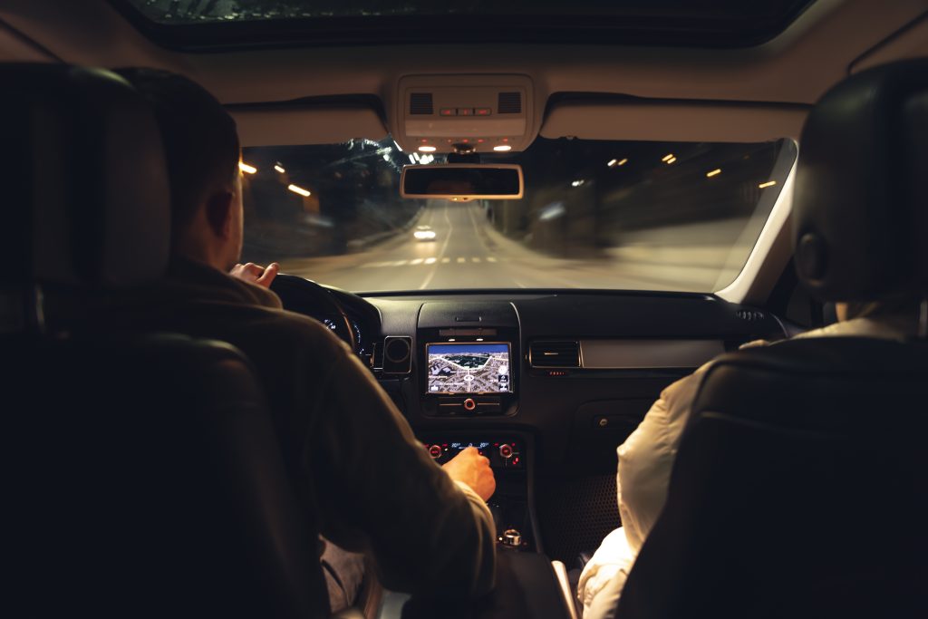 Nighttime car interior with driver and GPS screen.