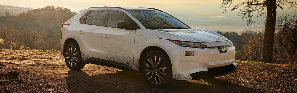 2026 Subaru Solterra electric SUV parked on a scenic hilltop overlook with sunset lighting and rugged landscape.